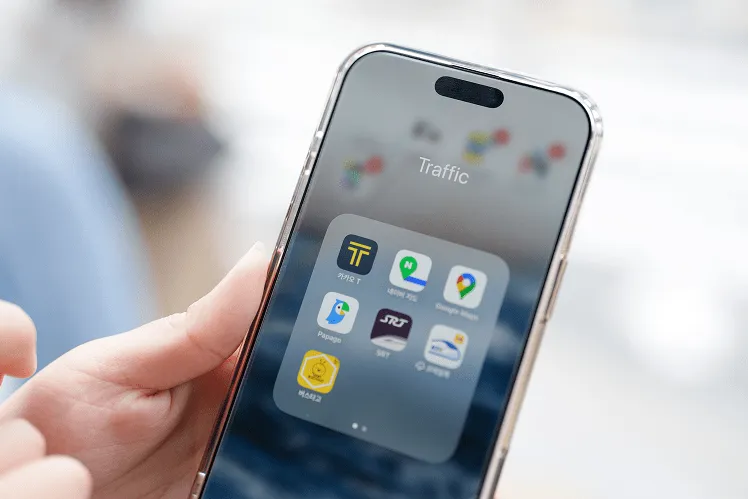 woman's hand pointing at a smartphone screen displaying popular apps like KakaoTaxi, Naver Map, and Google Maps, with icons glowing brightly in the foreground