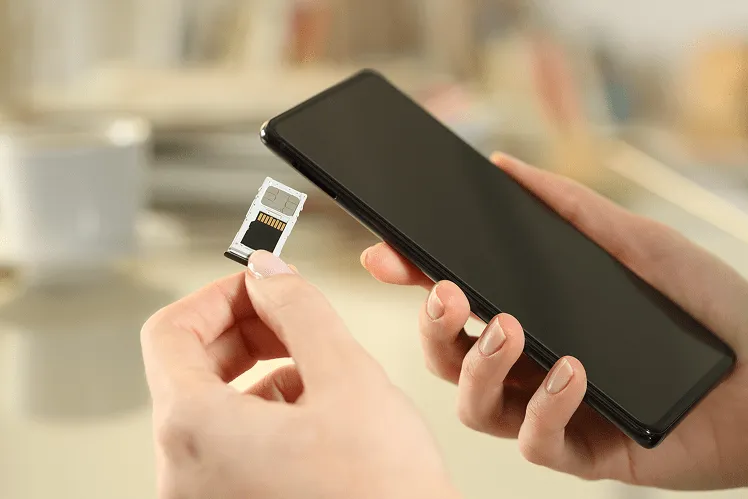 A young traveler girl carefully inserts a physical SIM card into her unlocked smartphone right after arriving at Incheon International Airport in South Korea