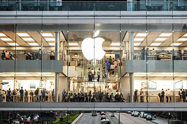 The massive illuminated Apple logo glows prominently on the expansive glass facade of the Apple Canton Road store, engineered with a 14-meter-tall glazed front for maximum transparency