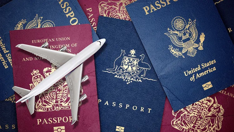 A small toy airplane rests on top of a pile of international passports in various colors, symbolizing global travel and connectivity